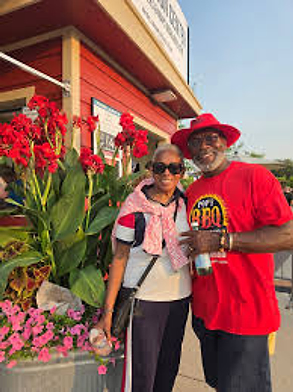 The husband and wife owners of Pop's BBQ standing together outside the truck
